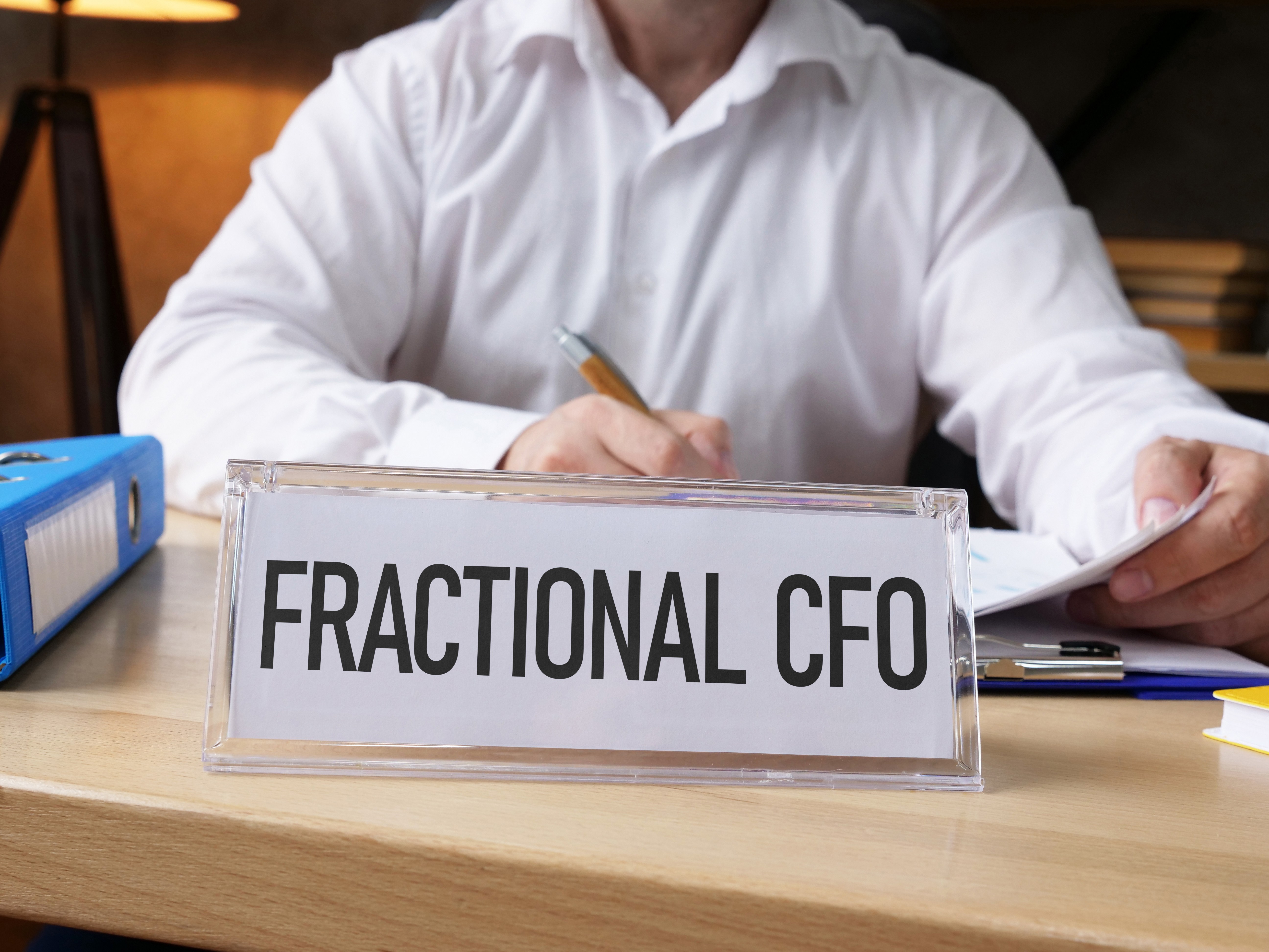 Executive at a desk reviewing financial documents behind a Fractional CFO nameplate